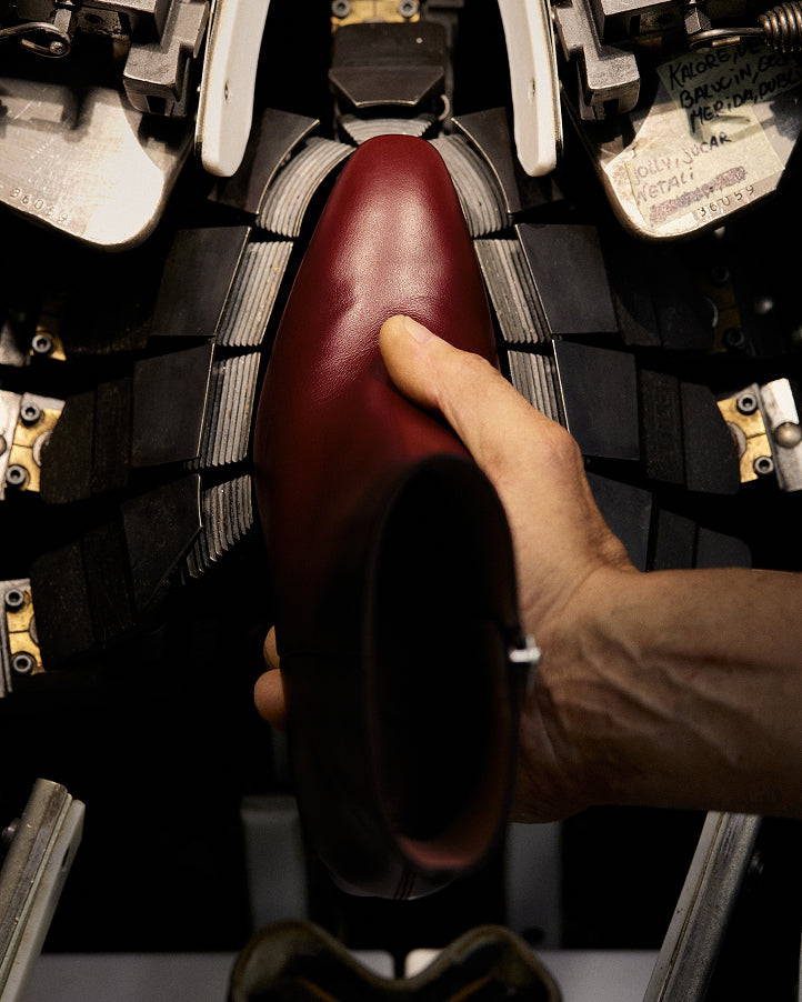 An artisan stitching an upper